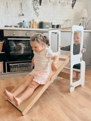 Adjustable-height Montessori helper tower with safety guardrails.