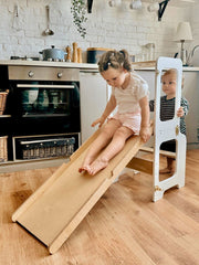 Adjustable wooden learning tower for kids in a modern kitchen setting.