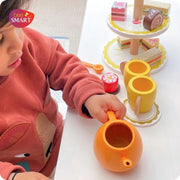 Wooden tea party set with teapot, cups, and cakes.