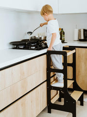 Black learning tower child cooking in kitchen