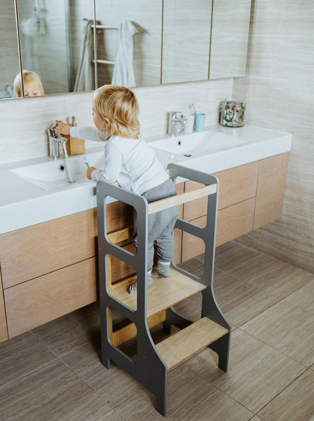 grey learning tower with child at bathroom sink
